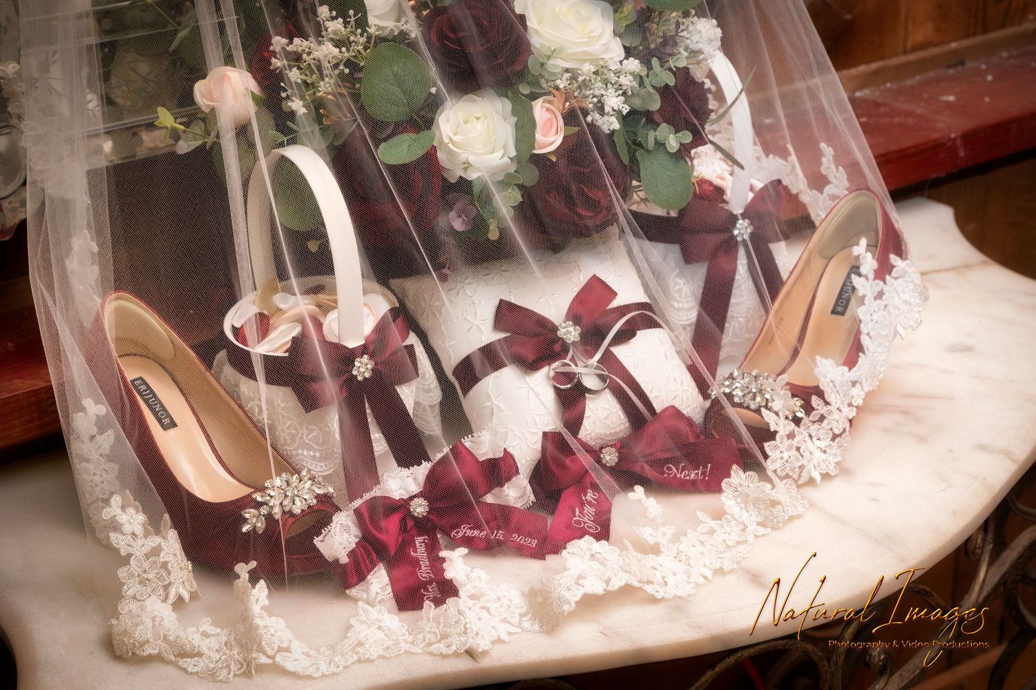 Elegant burgundy and white bridal accessories including shoes and flowers displayed together.