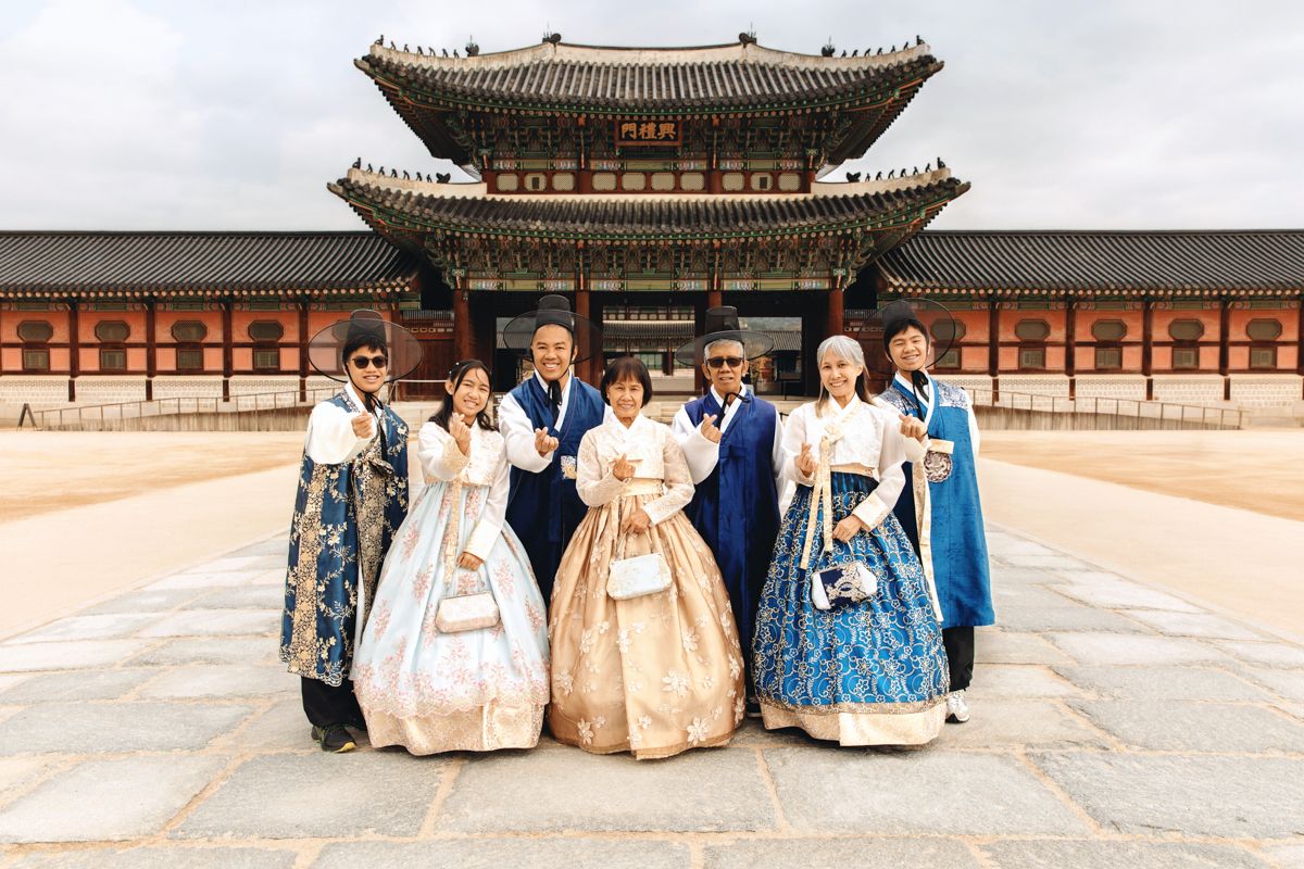 A group stands in traditional Korean hanbok dress in front of Gyeongbokgung Palace in Seoul.