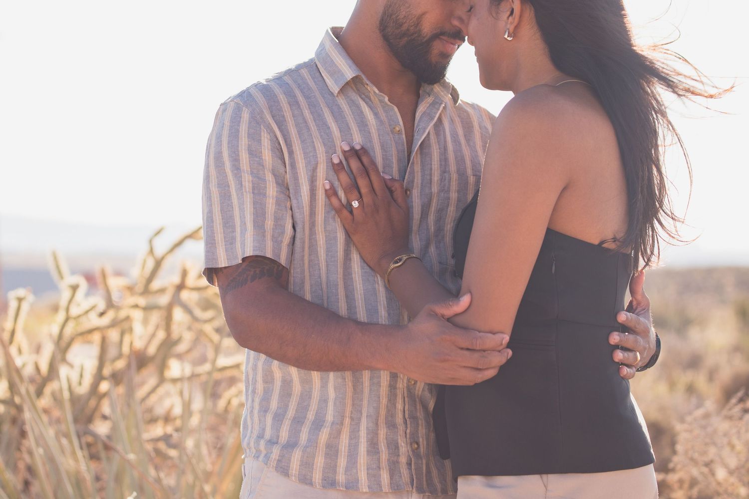 Couple embracing in golden field during sunset.
