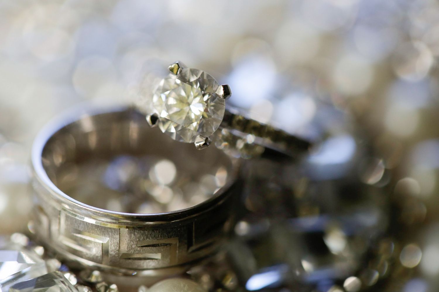 Close-up of sparkling wedding rings displayed on reflective surface.