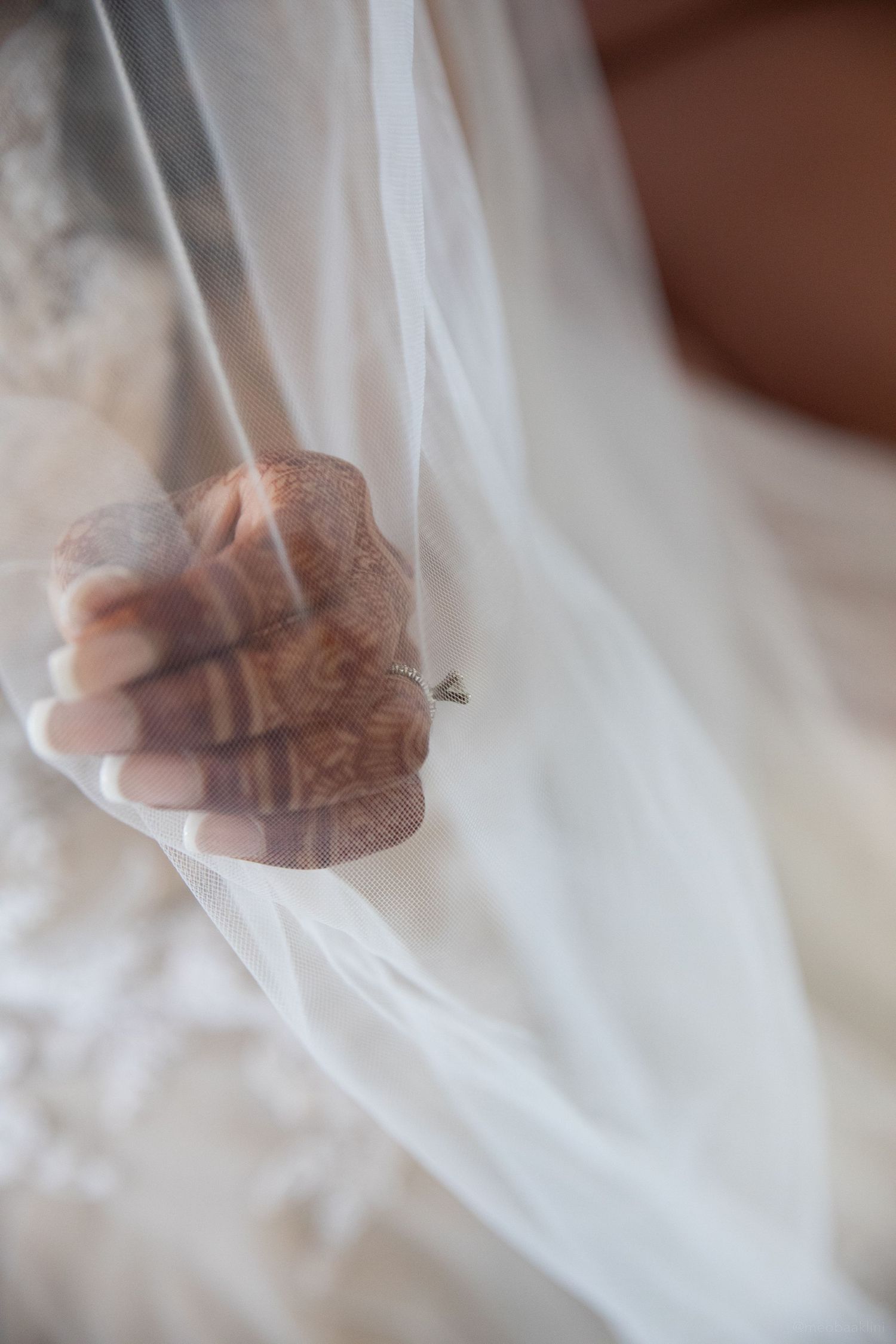 A close-up of hands holding a delicate white veil with intricate details.
