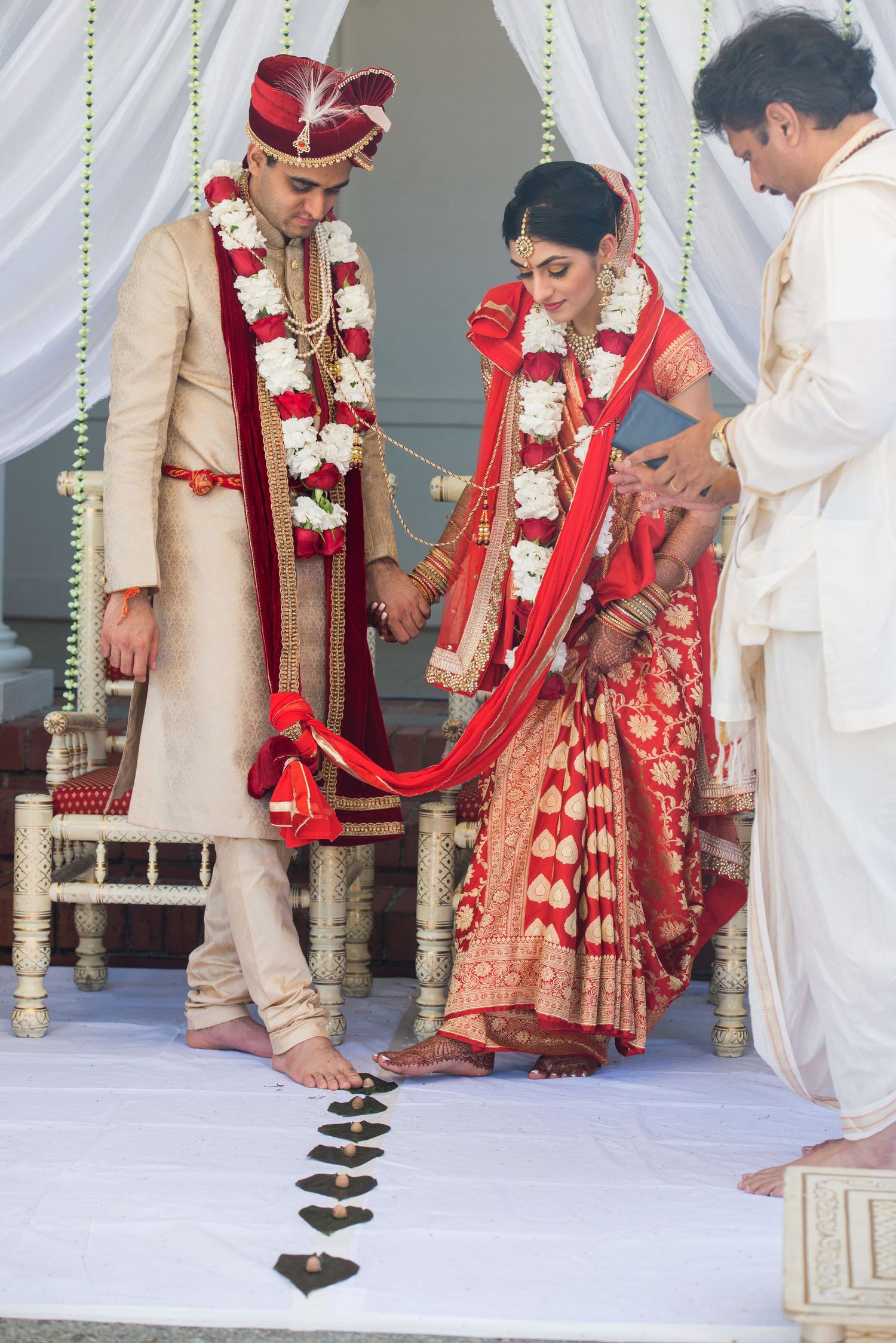 Wedding ritual showing traditional Indian ceremony steps on decorated white stage.