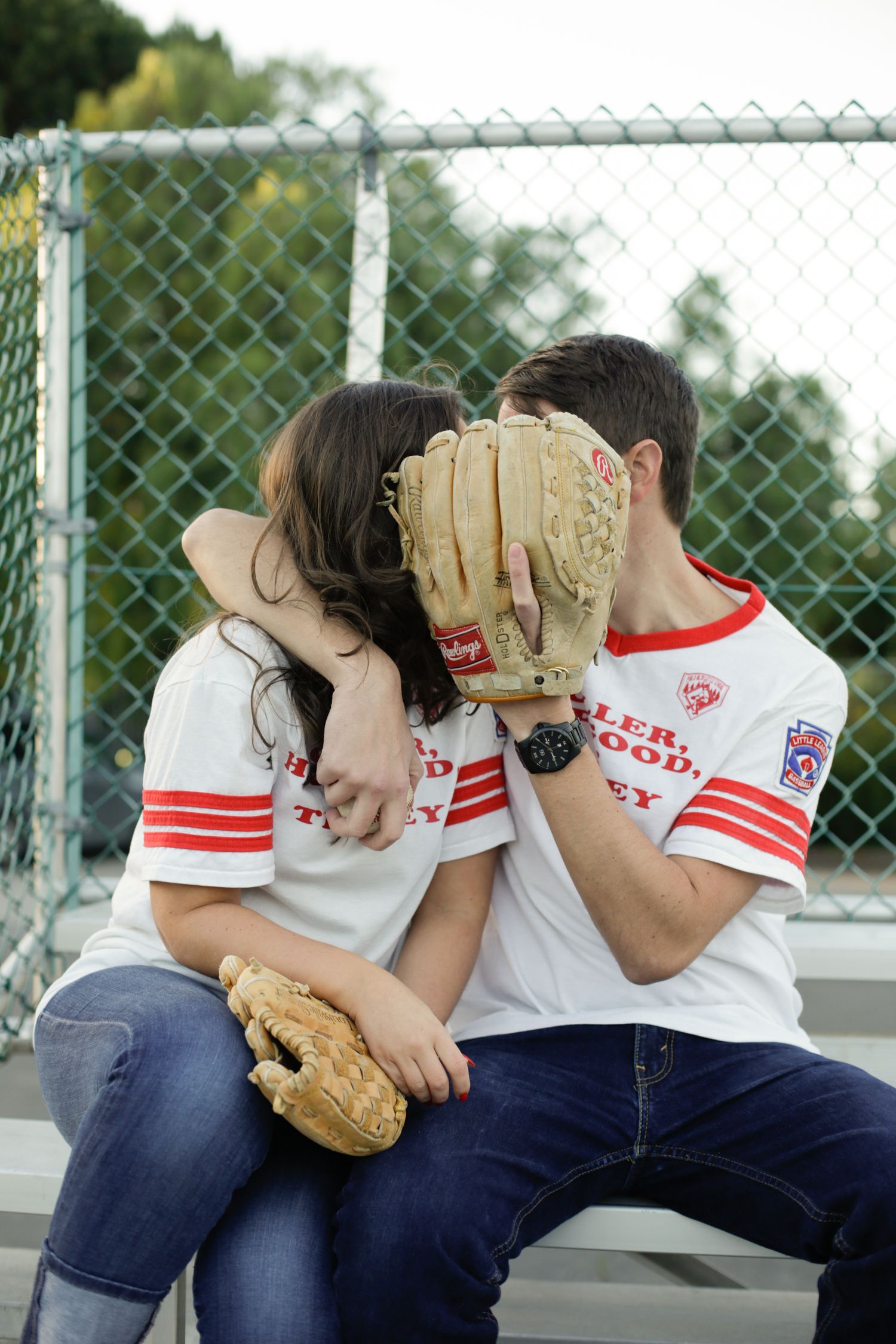 Young couple in matching baseball uniforms sharing a playful moment on a sunny day.