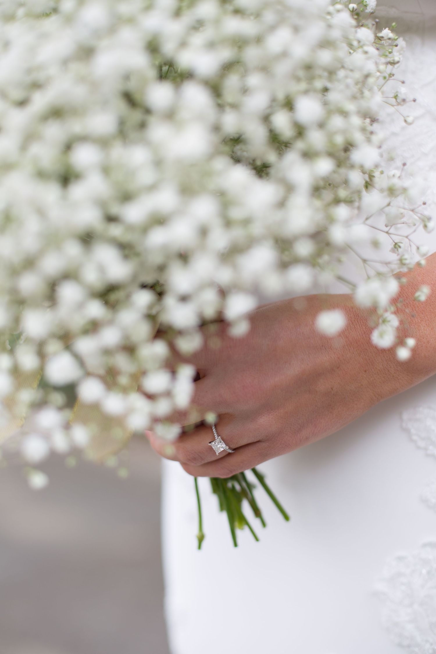 Delicate baby's breath bouquet held by hand wearing elegant engagement ring.