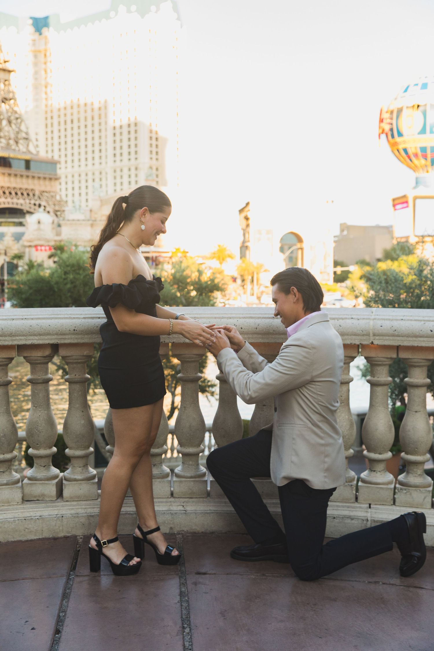 A romantic proposal scene on a balcony with the Las Vegas strip in the background.