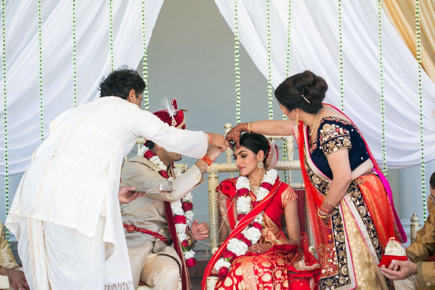 Traditional Indian wedding ceremony taking place with ritual blessings and garlands in a decorated mandap setting.
