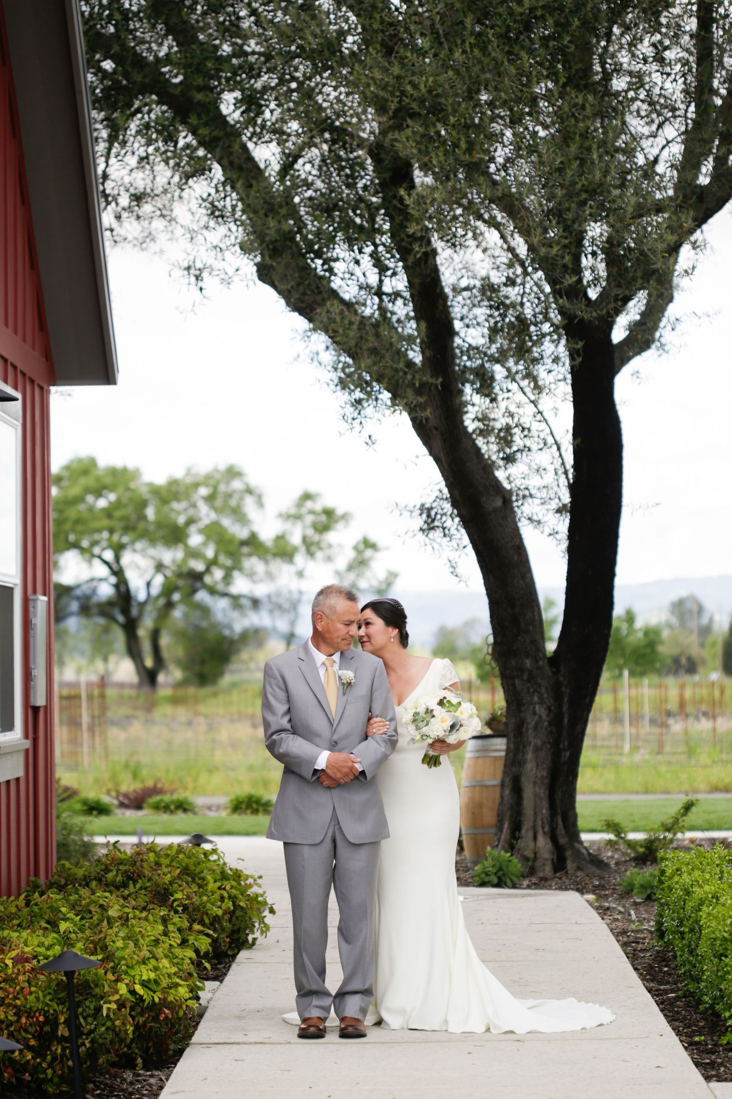 Elegant outdoor wedding ceremony with red architectural details framed by mature trees.