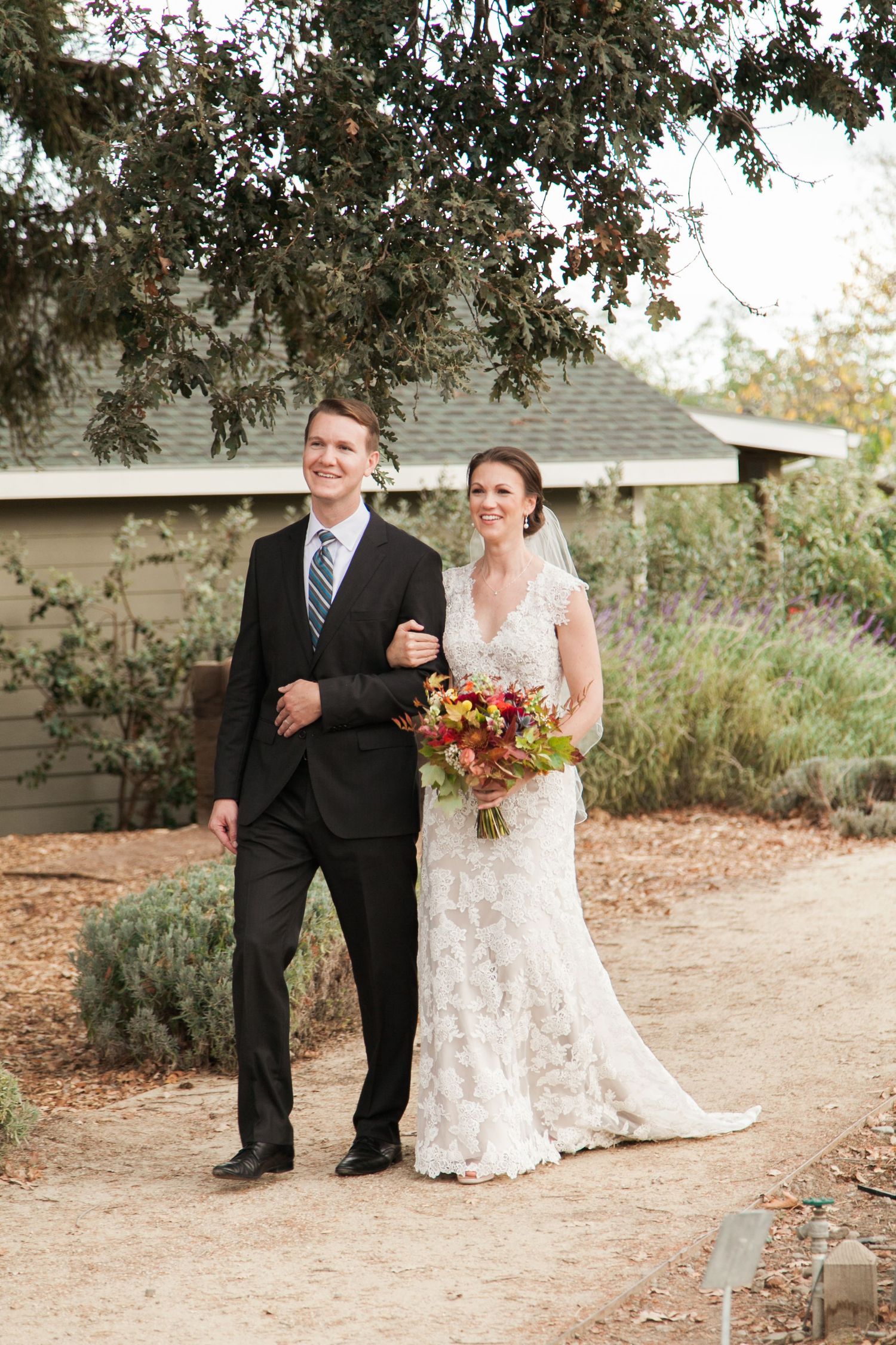 Wedding couple walking together on outdoor garden path.