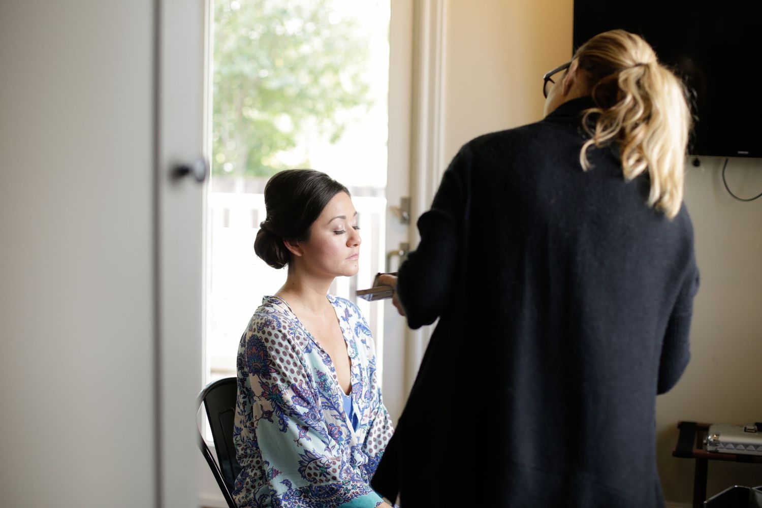 People getting ready in a sunlit room with white windows and casual atmosphere.