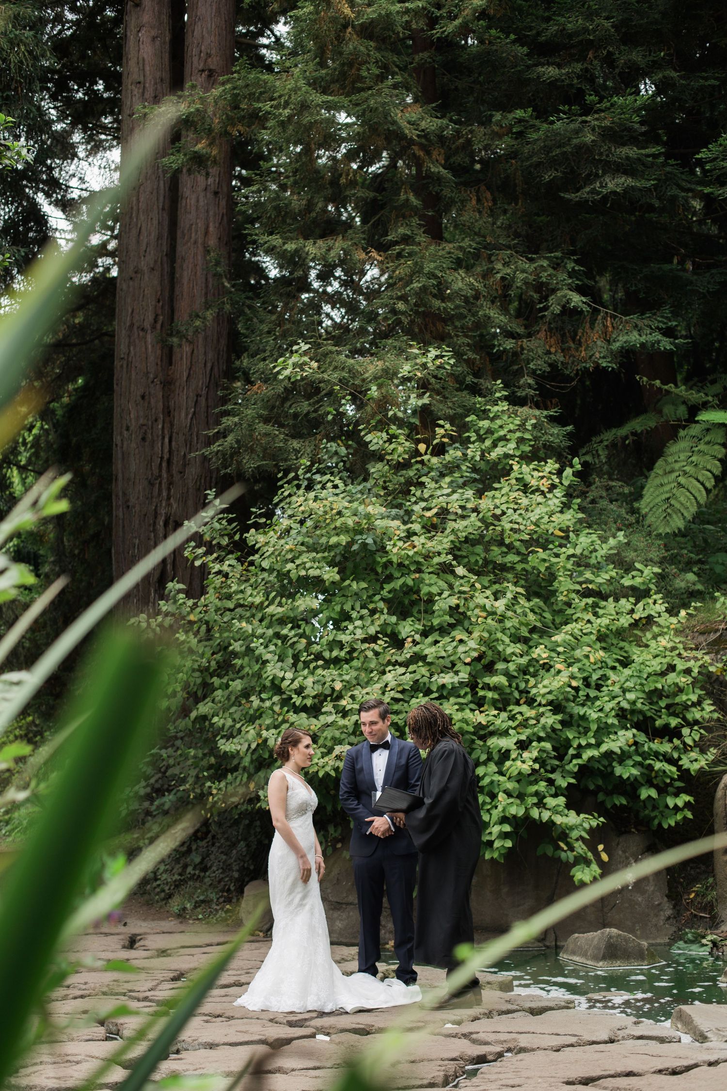 Wedding ceremony in a lush green forest setting with tall redwood trees.