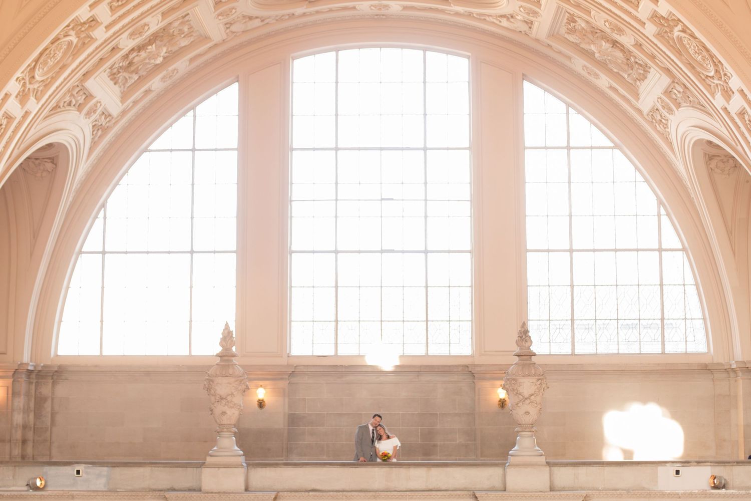 Interior view of an ornate historic building with grand arched windows and elegant architectural details.
