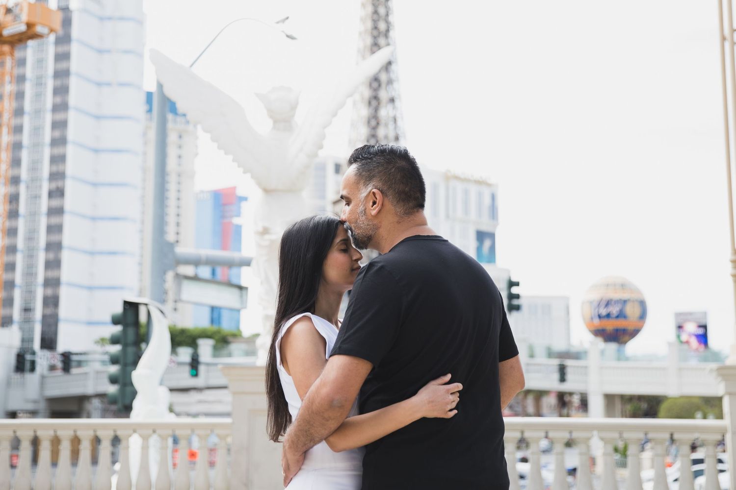Romantic moment captured between couple against modern city backdrop.