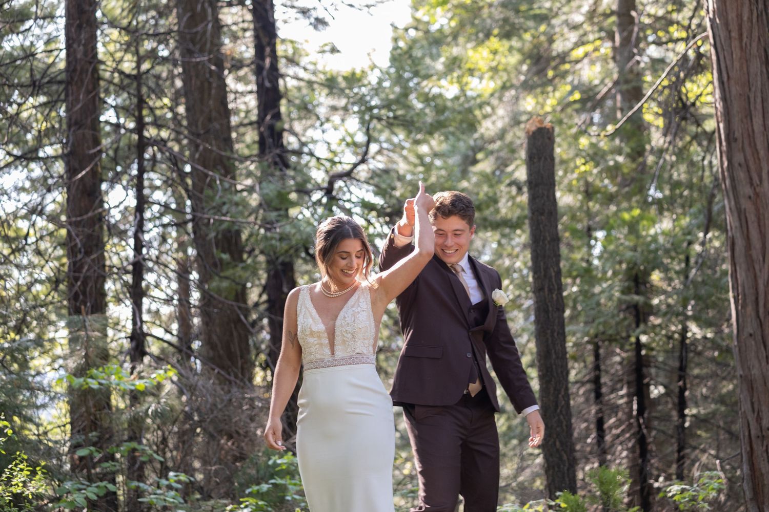 Couple walks hand in hand through a wooded outdoor wedding venue.