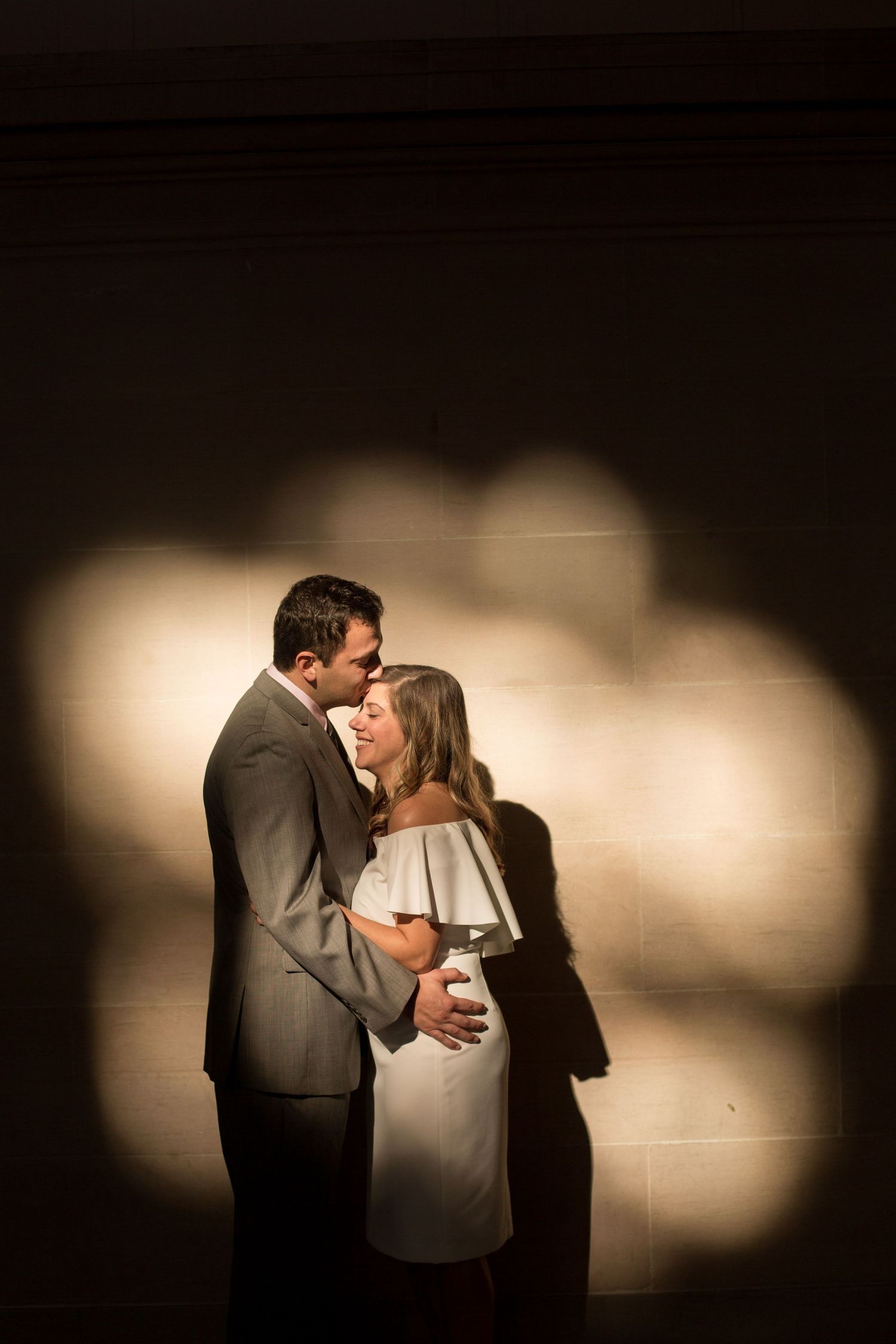 Artistic silhouette of couple embracing against dramatic lighting and shadows.