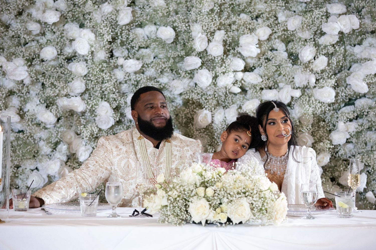 Wedding party members gathered at a table with elegant white floral arrangements and decor.
