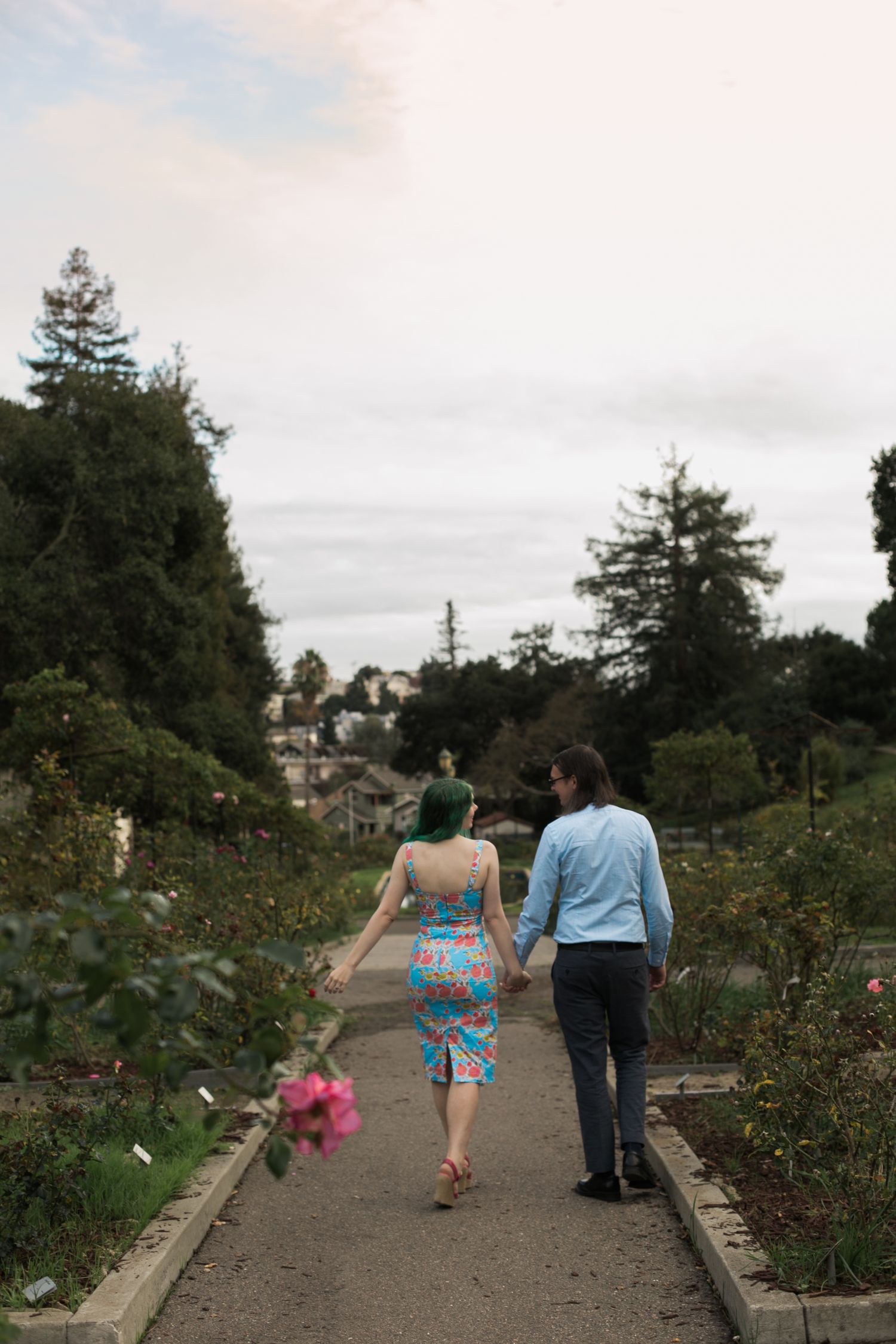 Couple walking together along a garden path on a cloudy day.