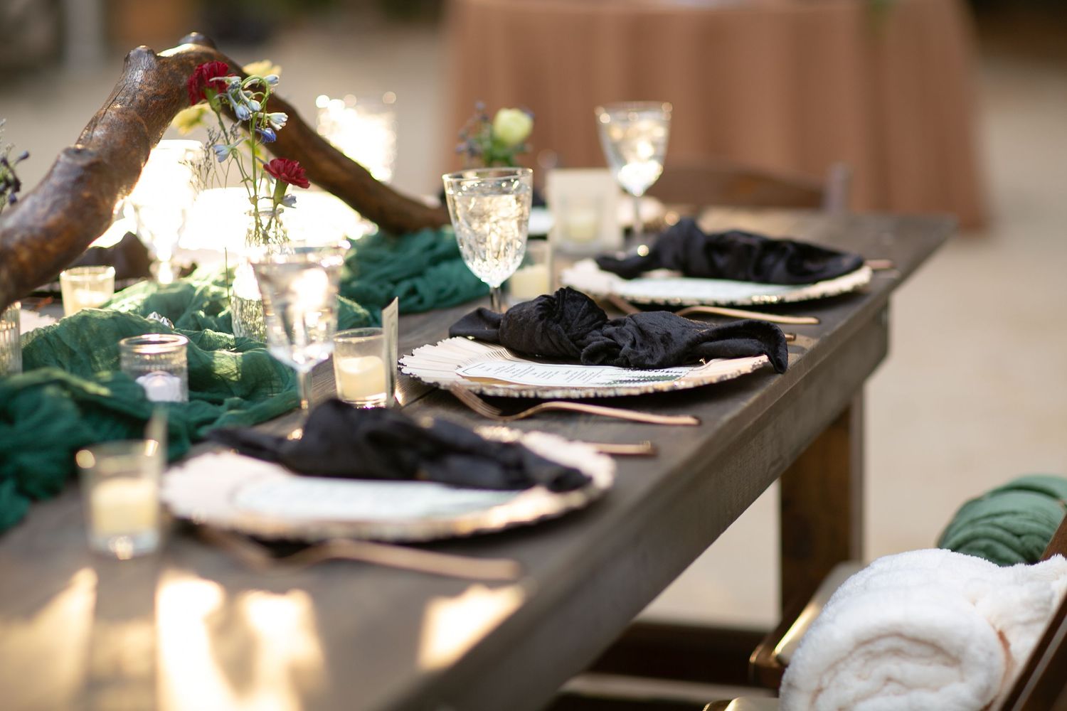 Modern wedding reception table with sleek black and gold place settings and ambient lighting.
