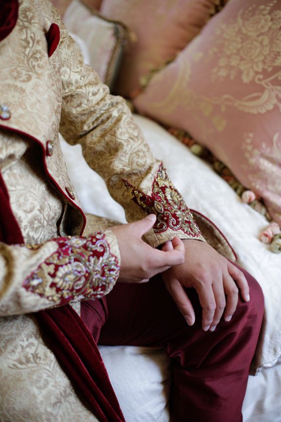 Close-up details of ornate cream and burgundy wedding attire with intricate embroidery.