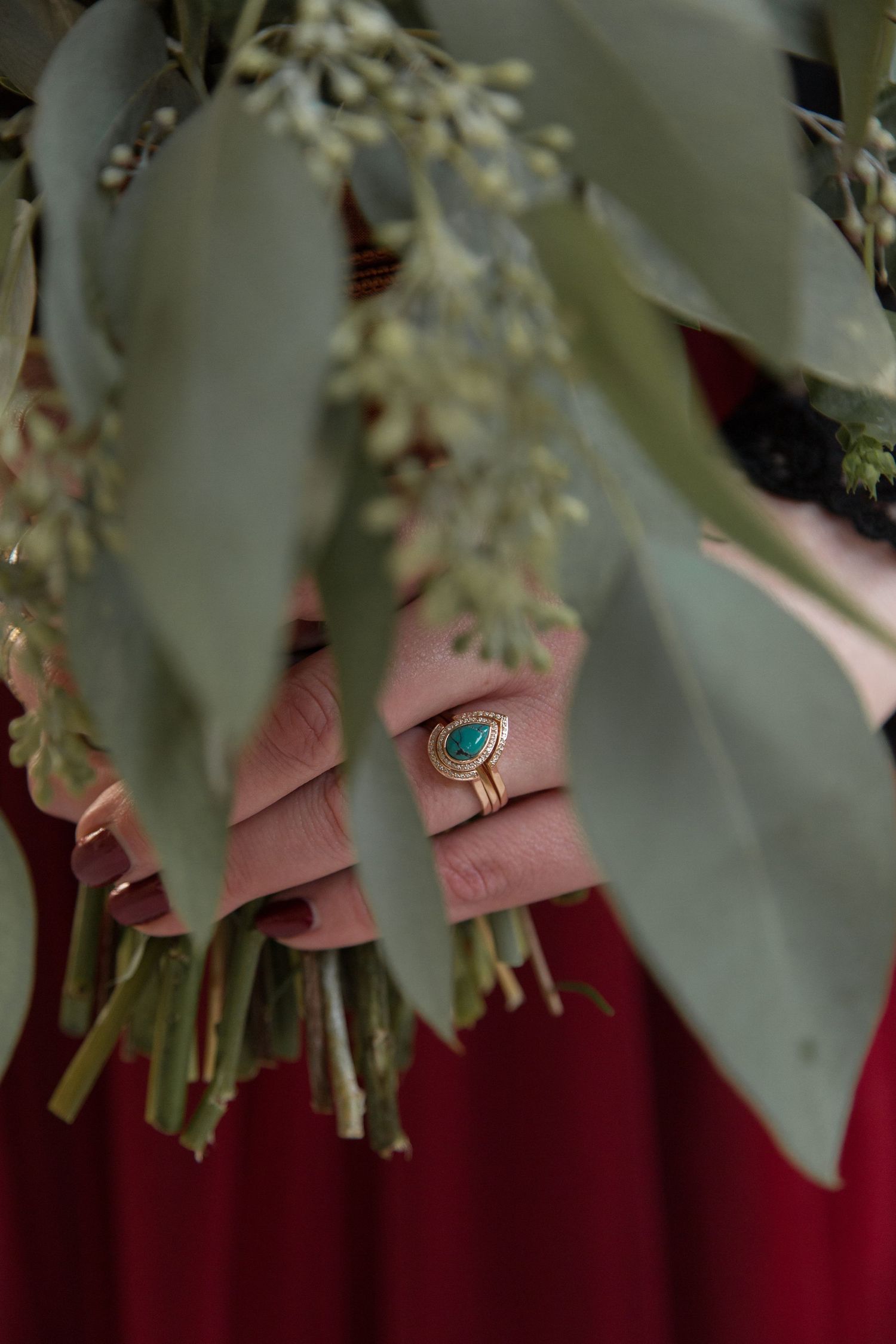 Close-up of an engagement ring with delicate greenery and white flowers in the foreground.