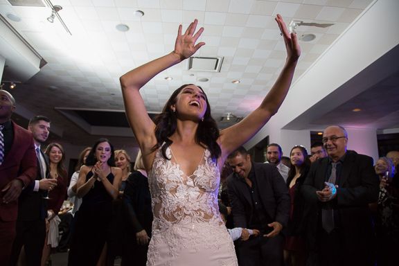 Lively wedding reception with dancing and celebrations under purple mood lighting.