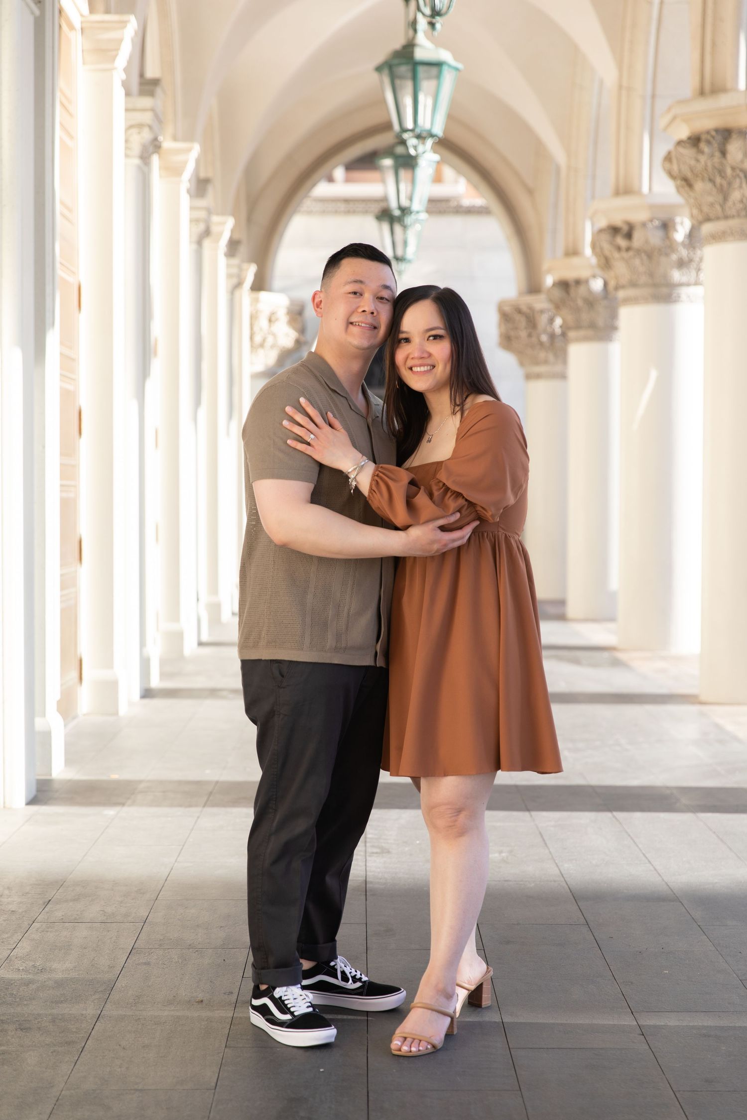 Couple sharing playful moment under elegant white archways.