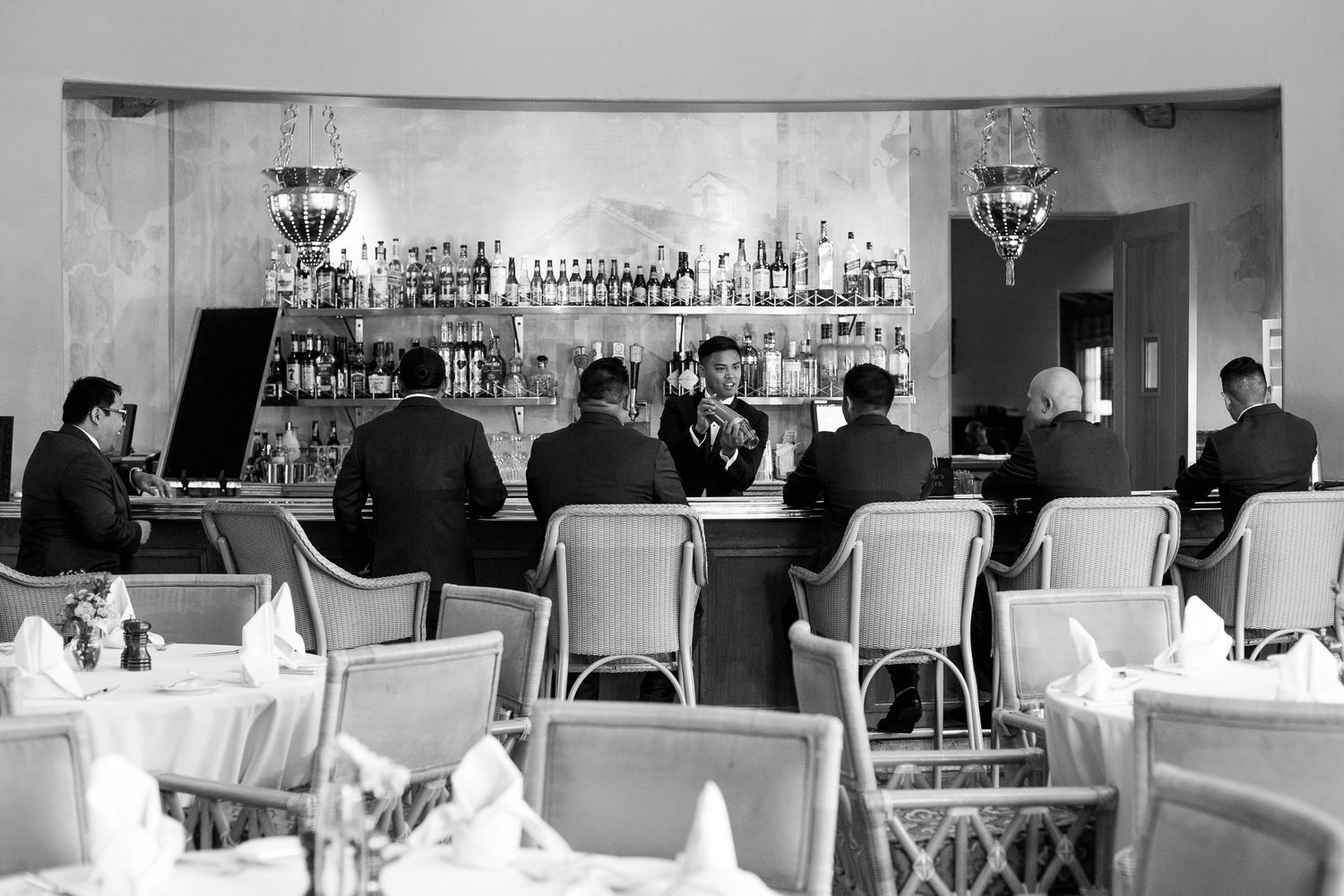 Vintage black and white photo of people seated at an elegant bar counter.