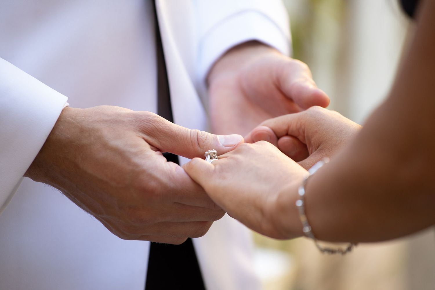 Close-up shot of hands exchanging wedding rings during a ceremony.
