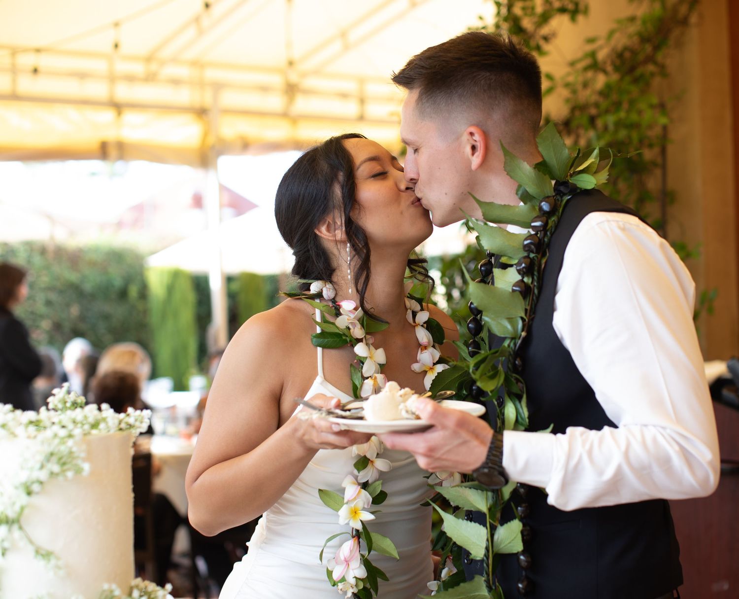 A couple shares a sweet moment while holding wedding cake at their reception.