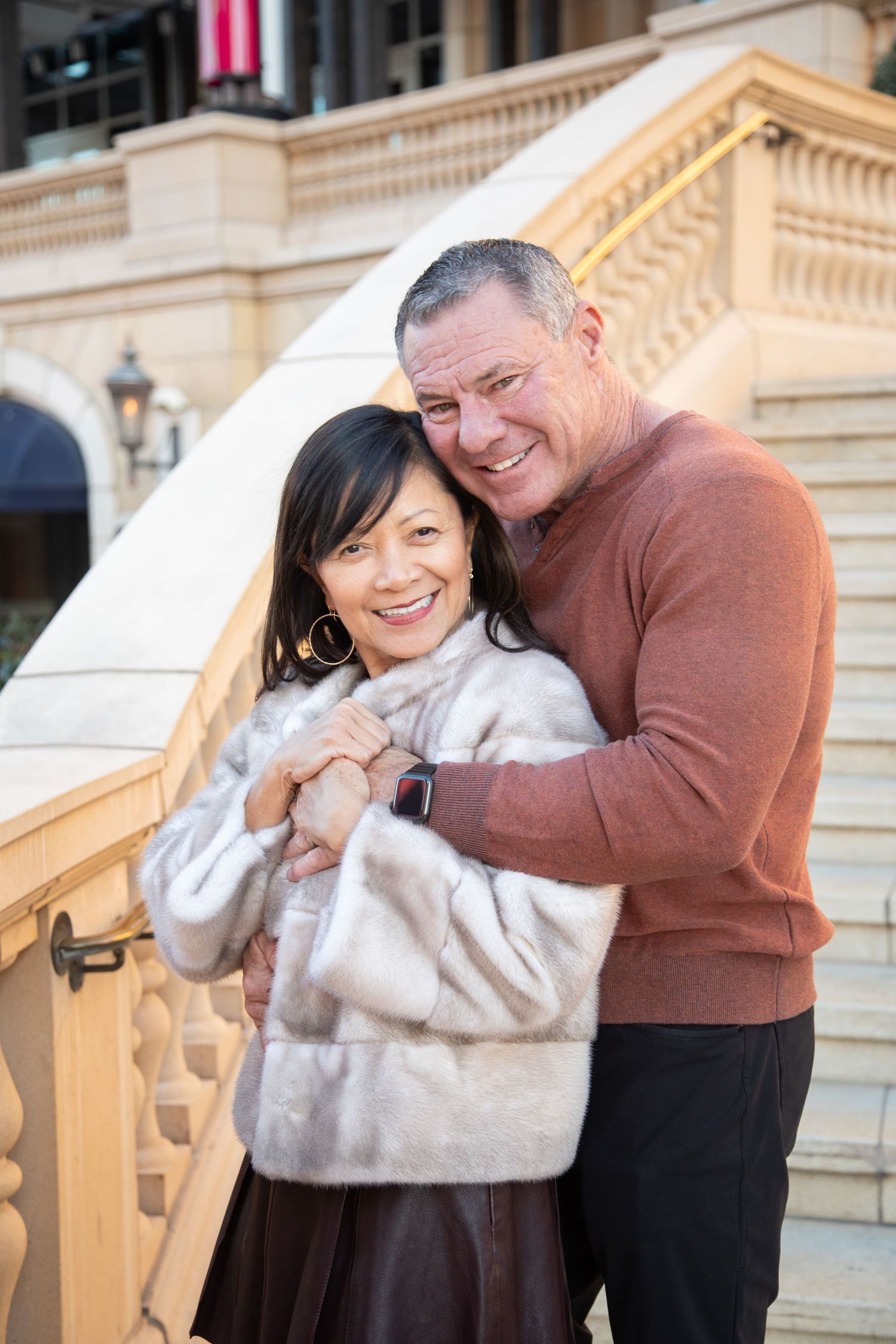 Couple sharing affectionate moment on ornate staircase with traditional architecture.