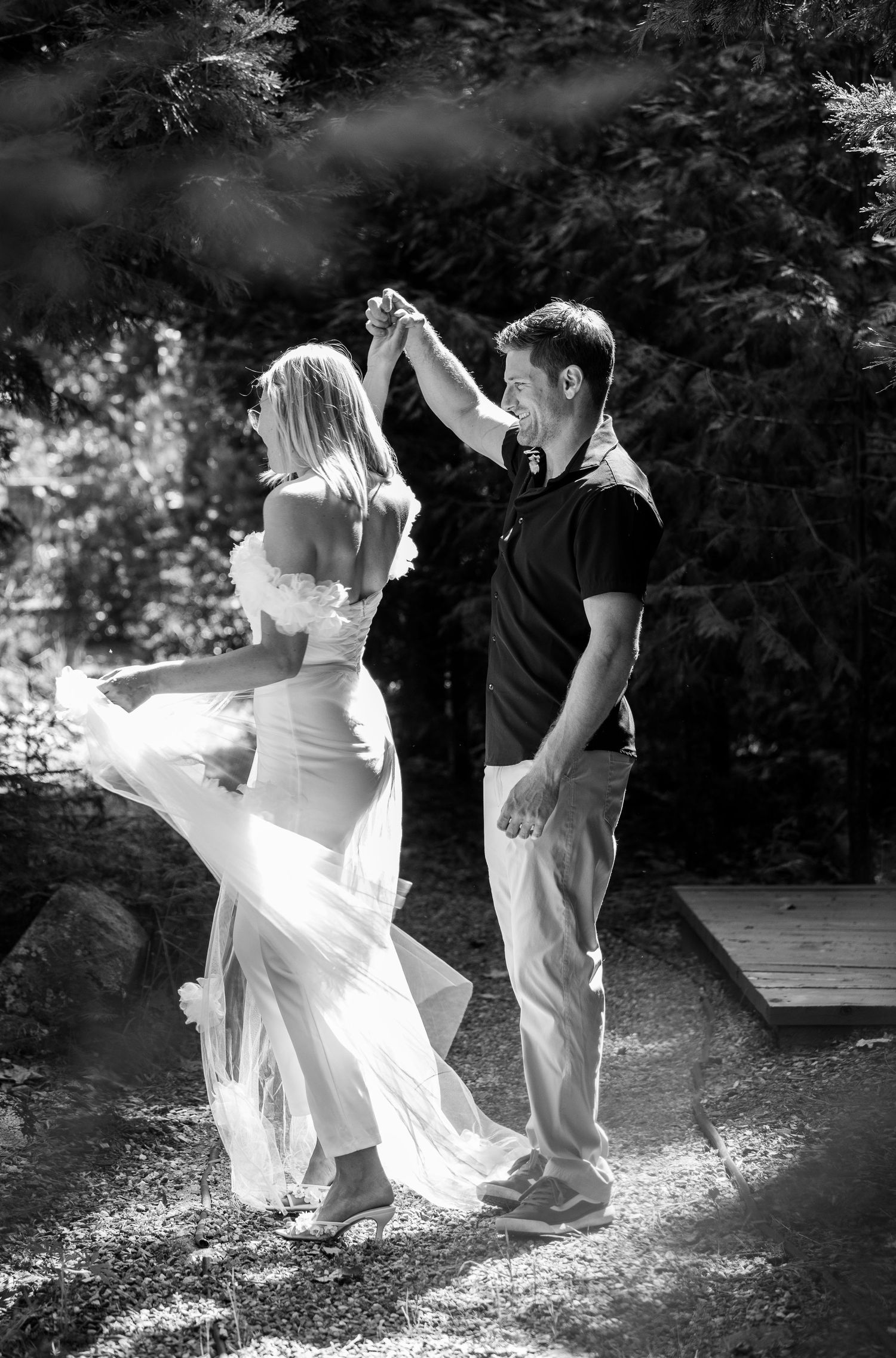 A black and white photo of a couple dancing outdoors with a flowing white dress.