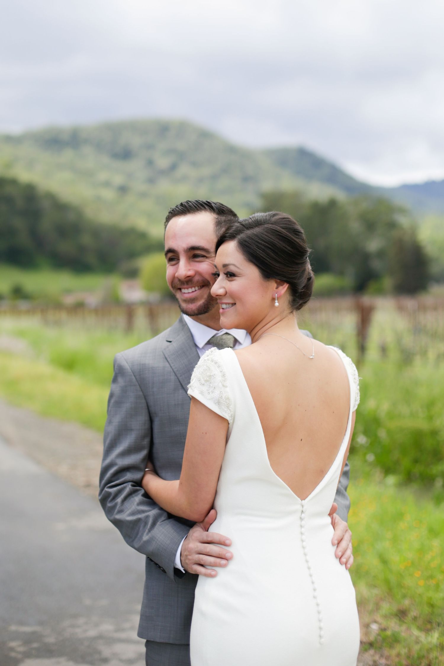 A couple sharing an intimate moment on a path with green mountains in the background.