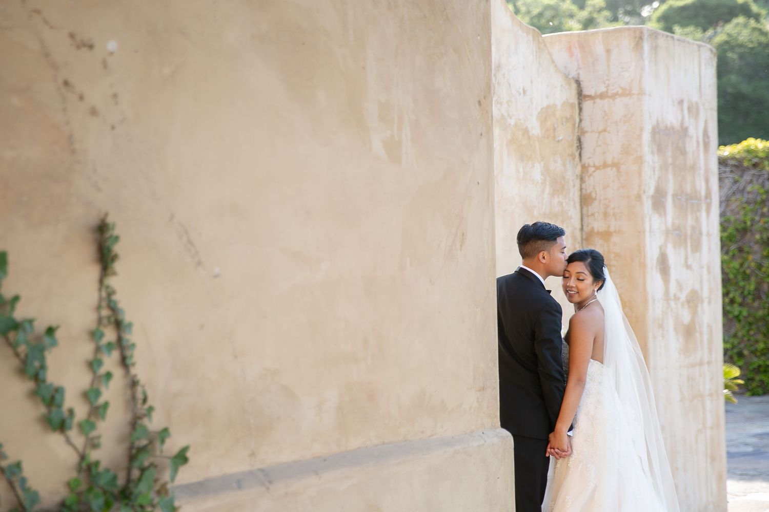 Intimate wedding portrait against textured stucco wall.