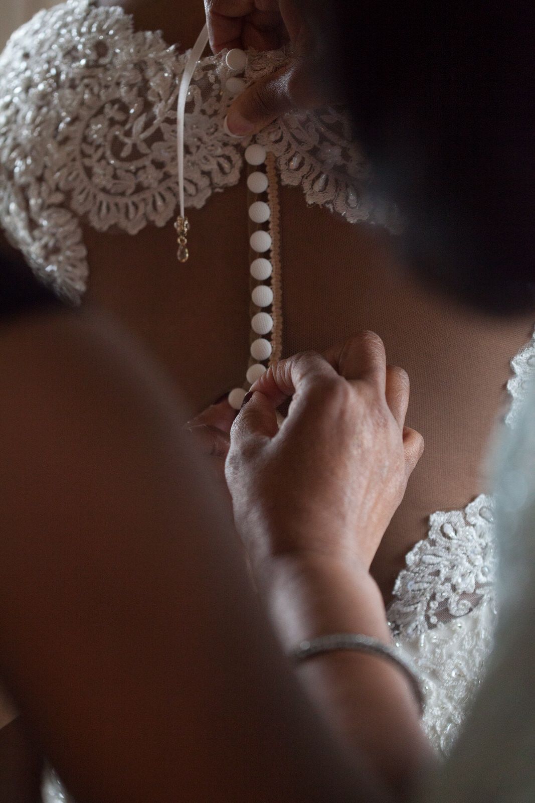 Close-up of buttoning a detailed lace wedding dress.