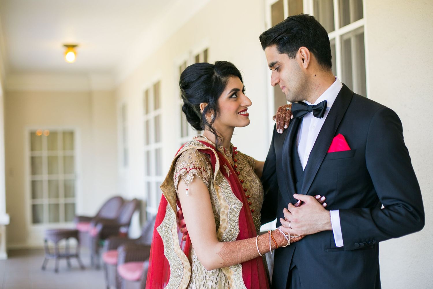 Couple shares an intimate moment in formal wedding attire combining traditional Indian and Western styles.