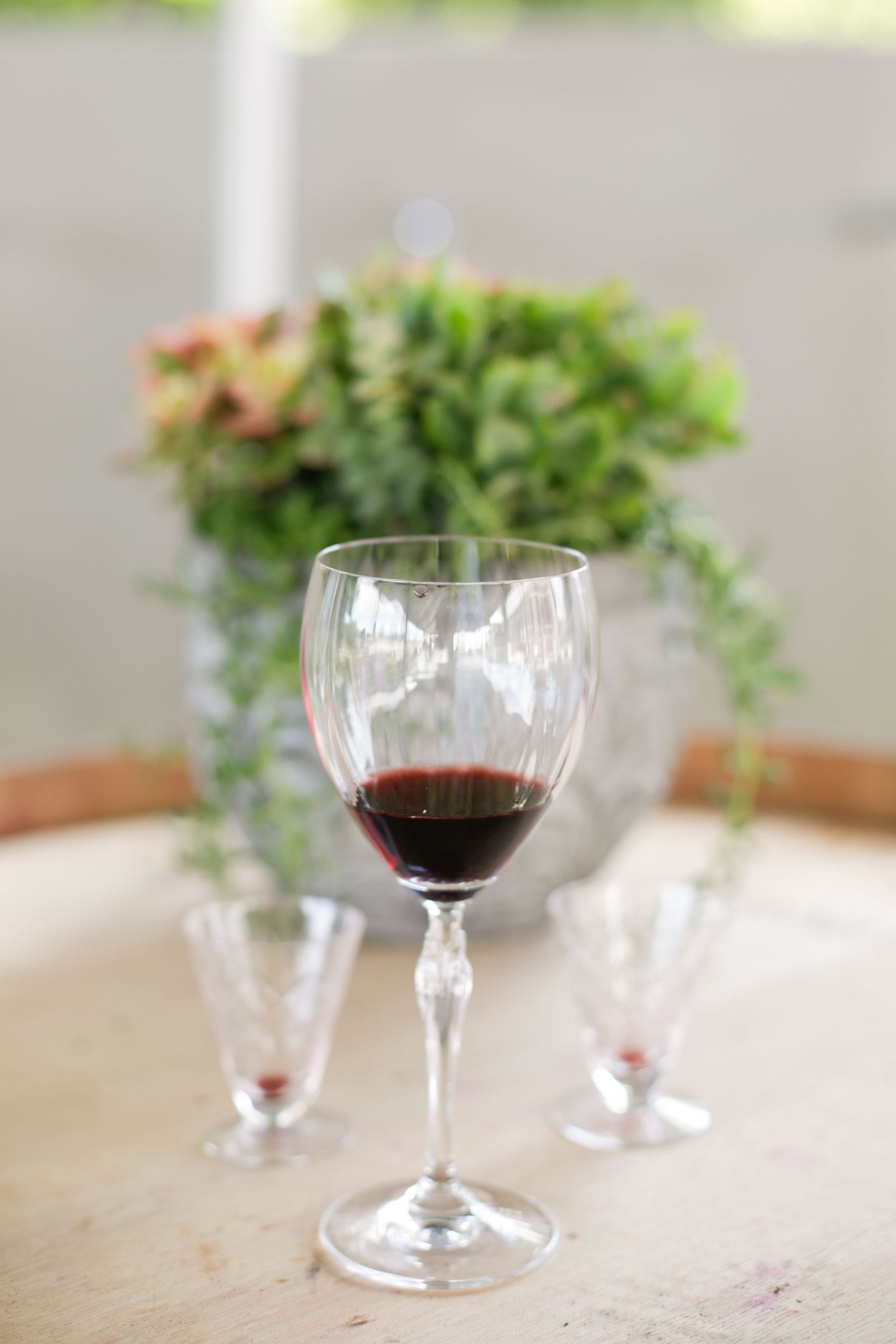 Wine glasses and greenery centerpieces arranged on wedding reception tables.