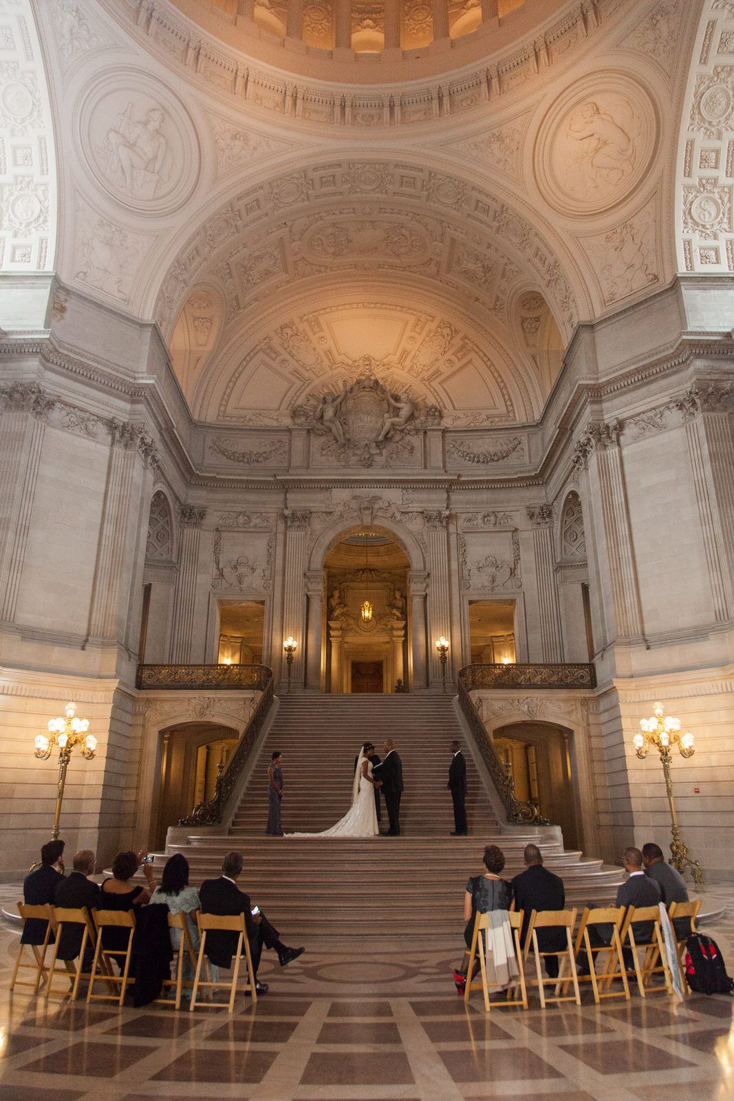 Grand marble staircase in ornate ceremonial hall with wedding ceremony setup.