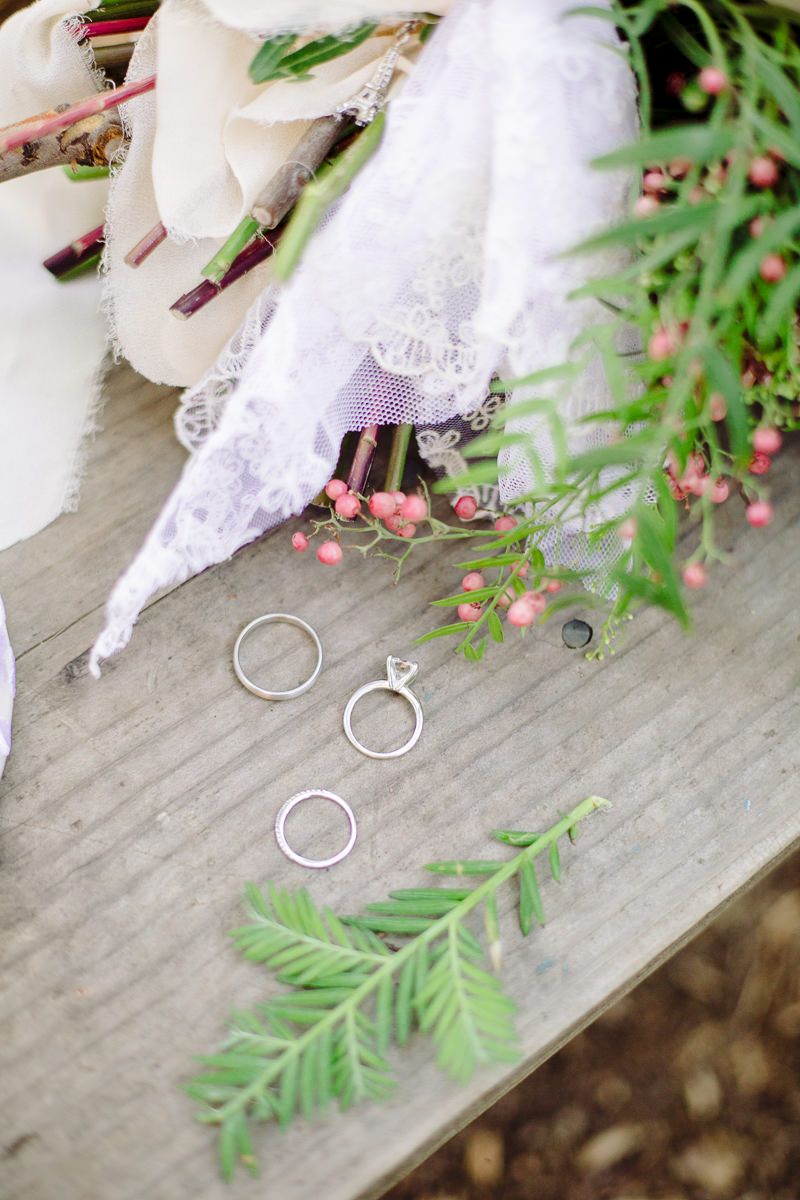 Wedding rings artistically arranged with delicate greenery and lace details.