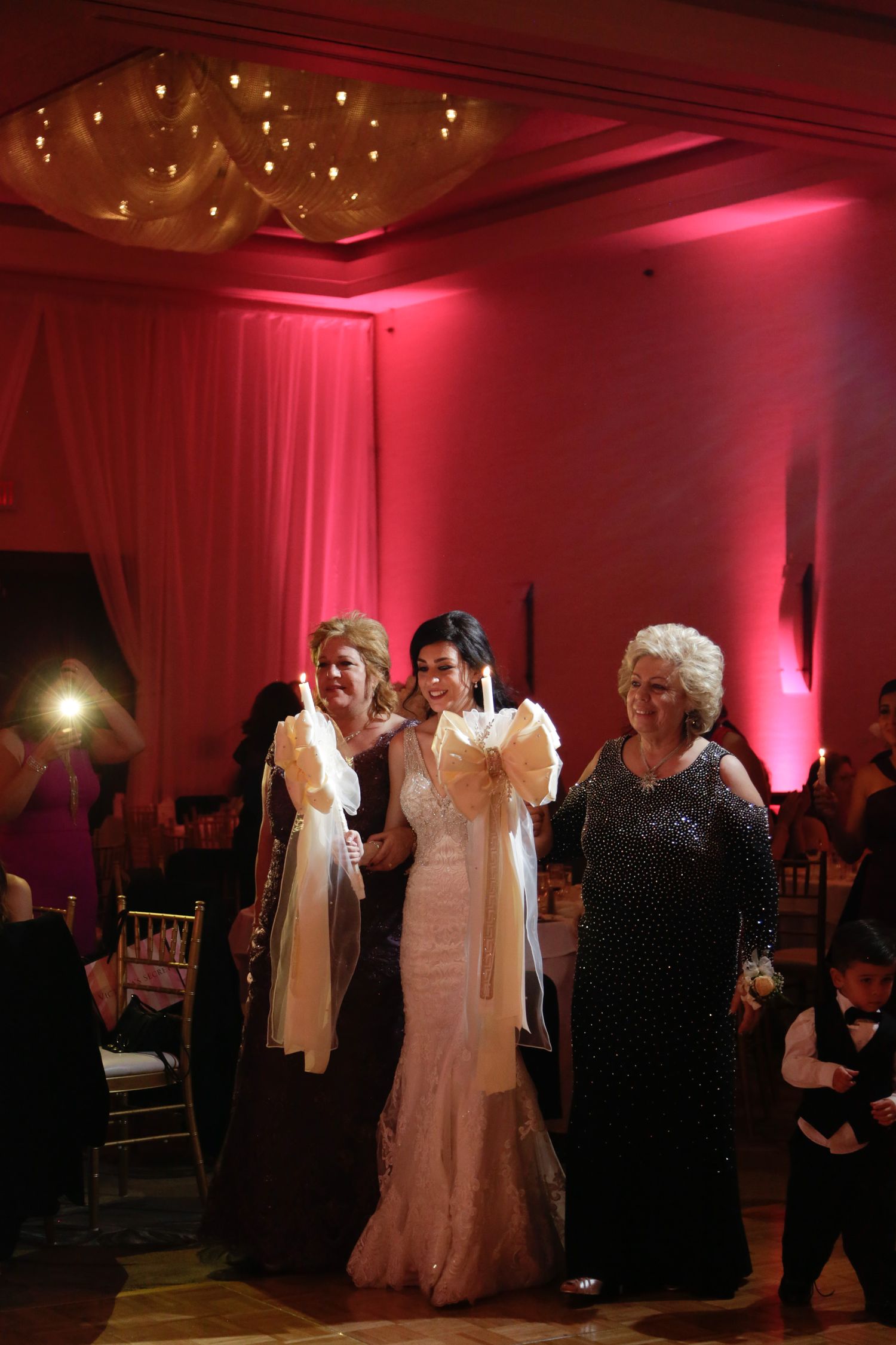 Wedding celebration in an elegant ballroom with dramatic red lighting and formal attire.