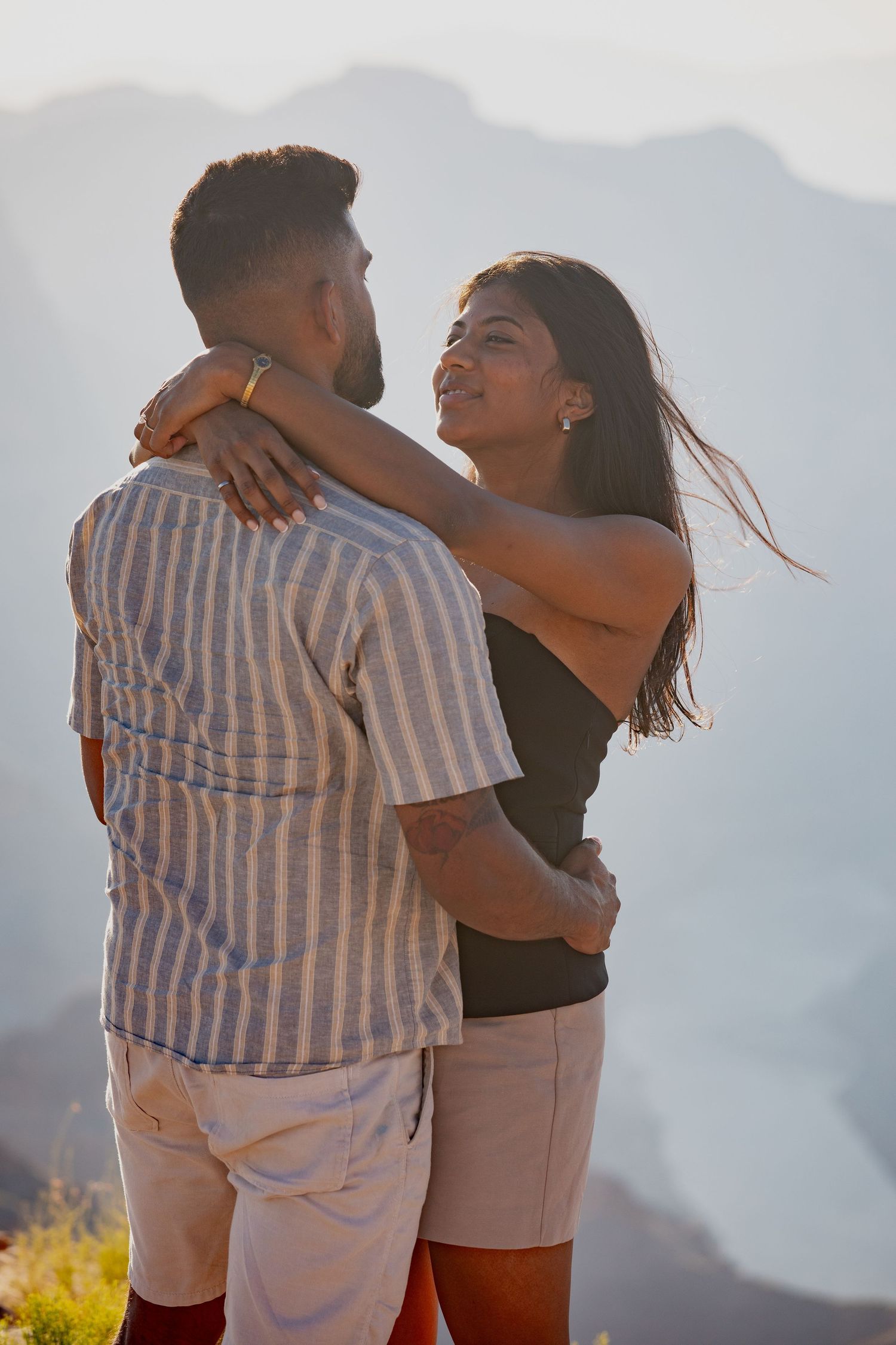 Happy couple embracing against mountain backdrop during sunset photo session.