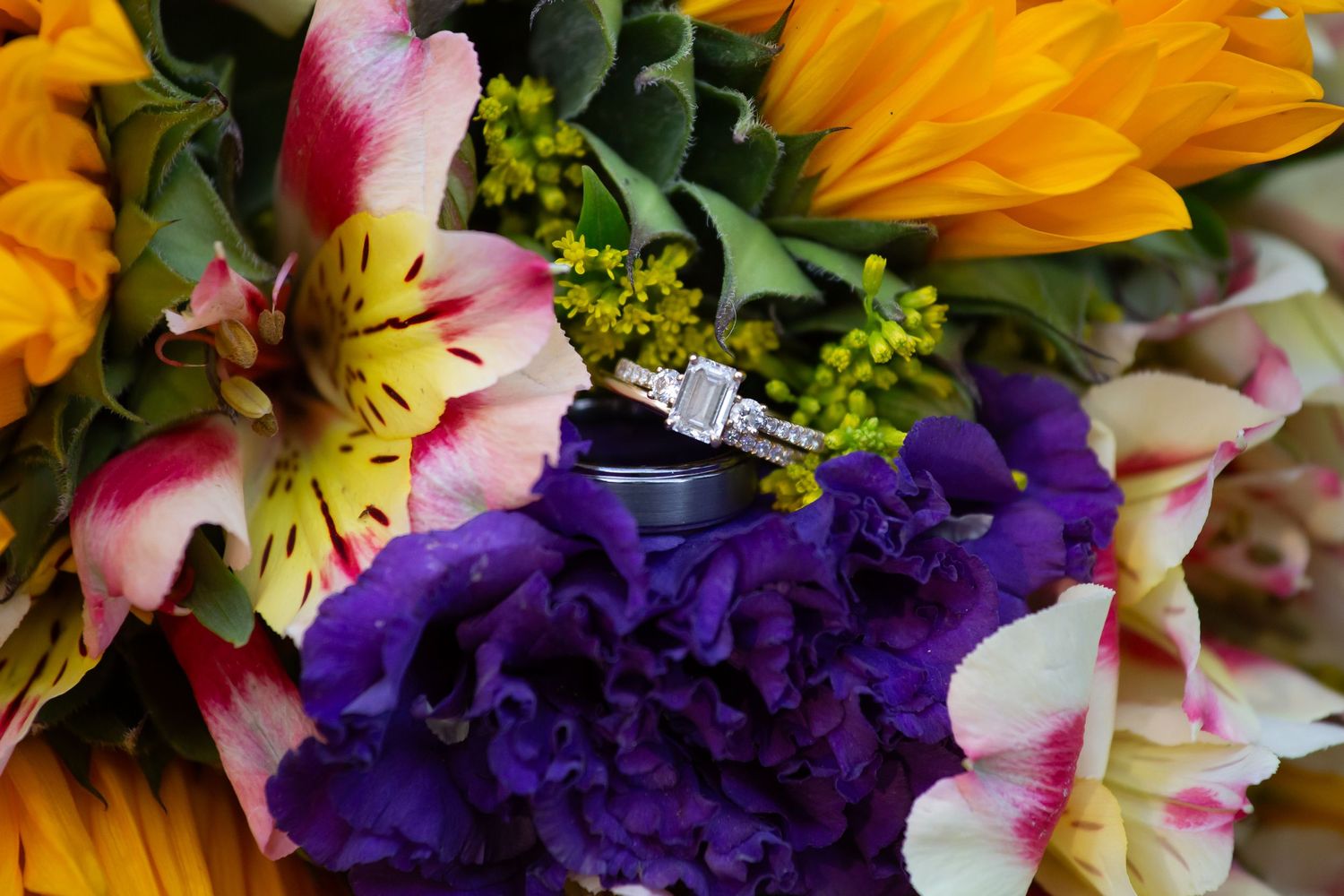 Vibrant wedding bouquet featuring purple, orange, and pink flowers with lush greenery.