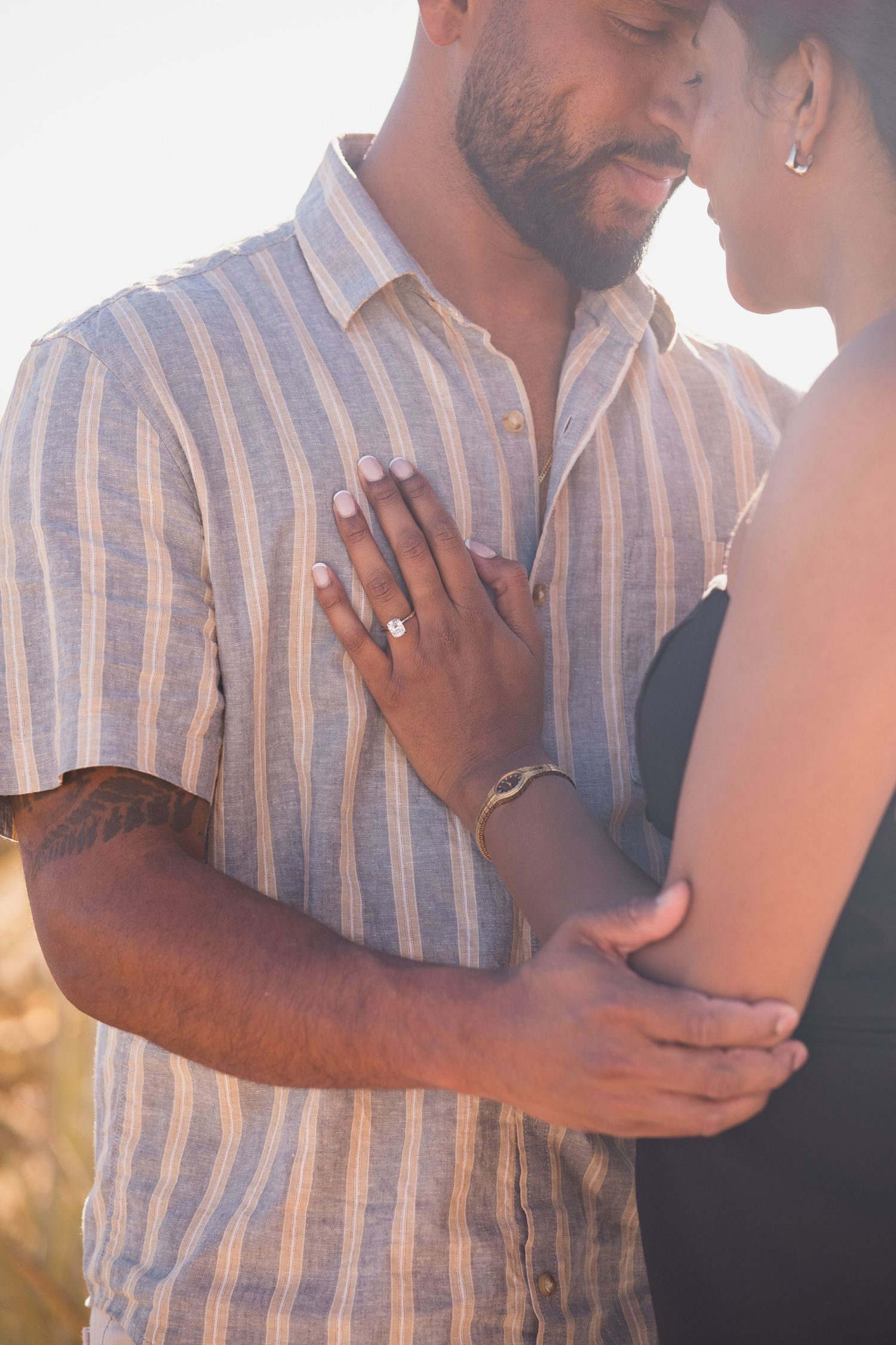 Close-up shot of couple embracing with hands tenderly placed during golden hour.
