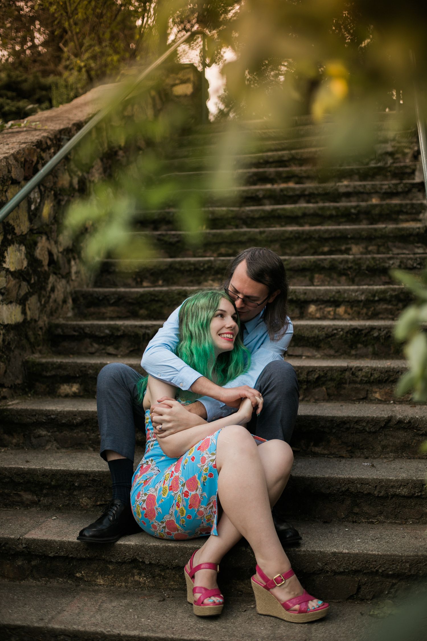 Couple sharing a tender moment while sitting on stone steps in a garden setting.