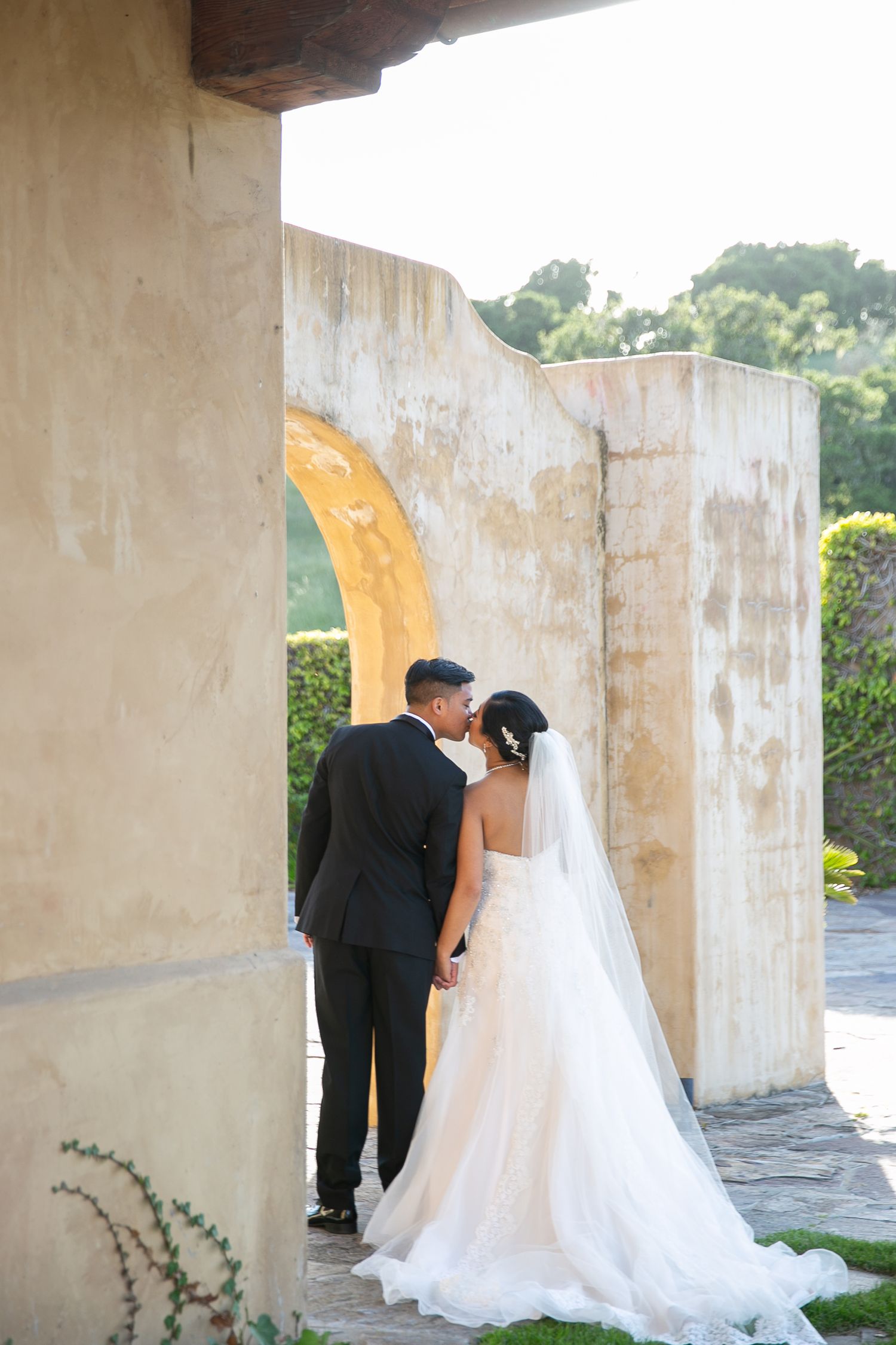 Wedding couple standing in archway of historic stone building.