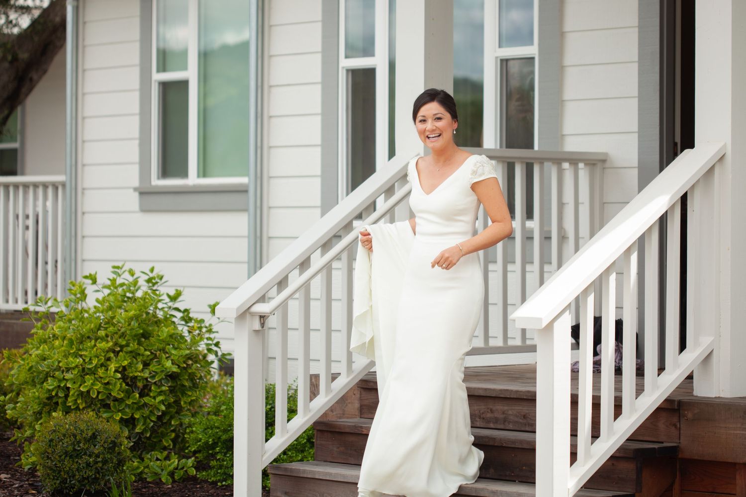 A view of white porch steps and railing against siding of a house.