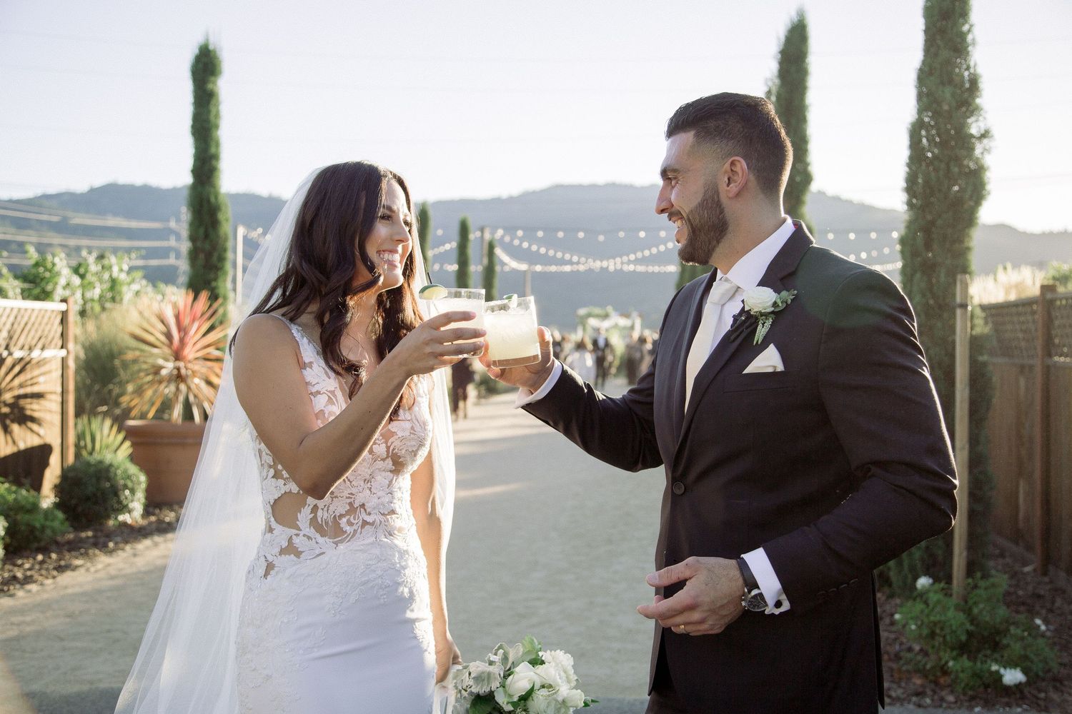 Romantic outdoor wedding portraits against mountain backdrop with string lights.