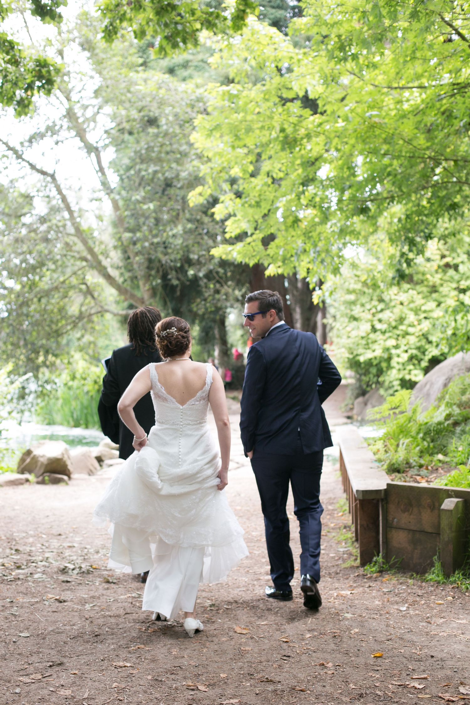 Couple walking down a tree-lined path after their wedding ceremony.