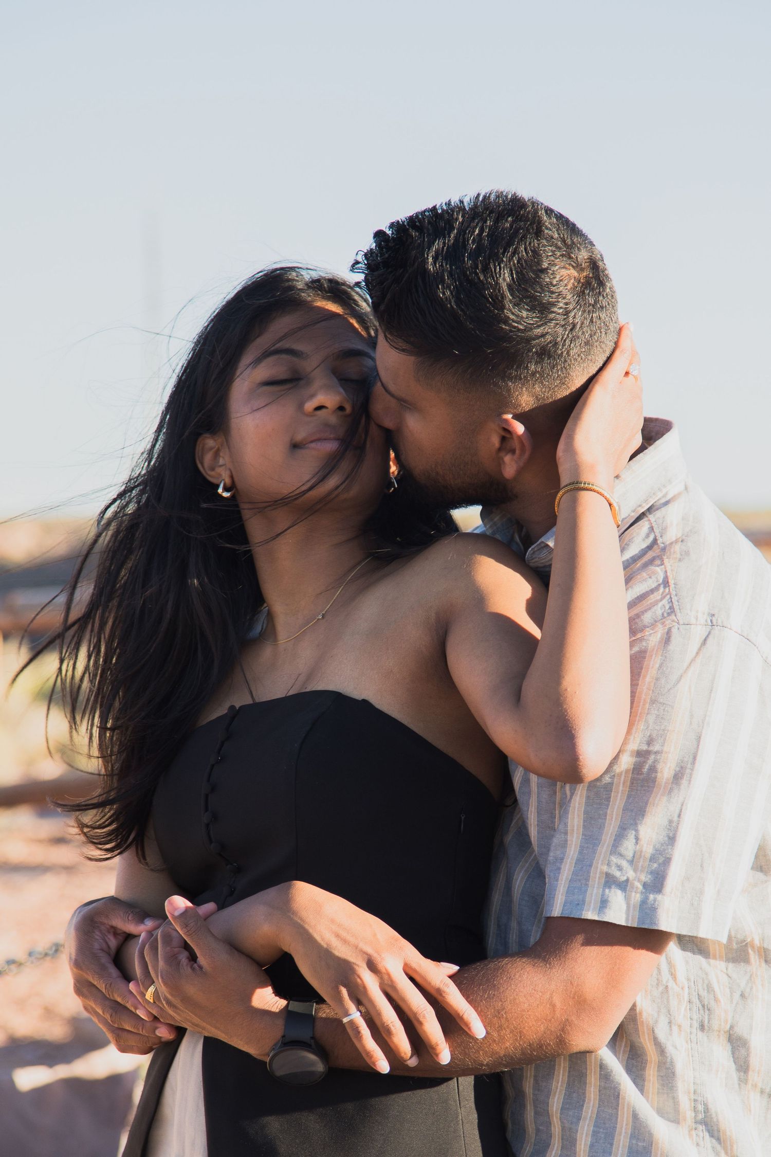 Romantic beachside portrait of couple in casual summer attire.