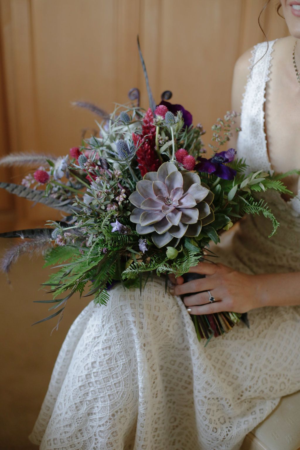 Beautiful wedding bouquet with succulents and mixed flowers against white lace fabric.