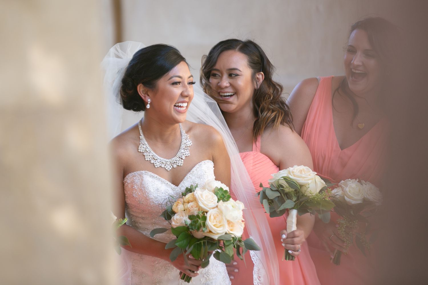 Joyful moment shared with bridesmaids holding bouquets in soft natural light.