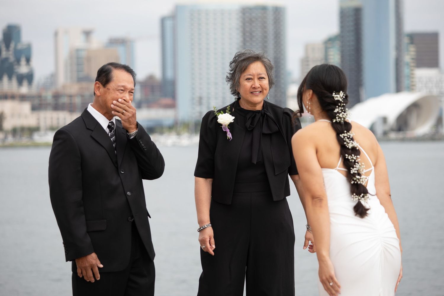 An emotional wedding moment shared between family members with city skyline in background.